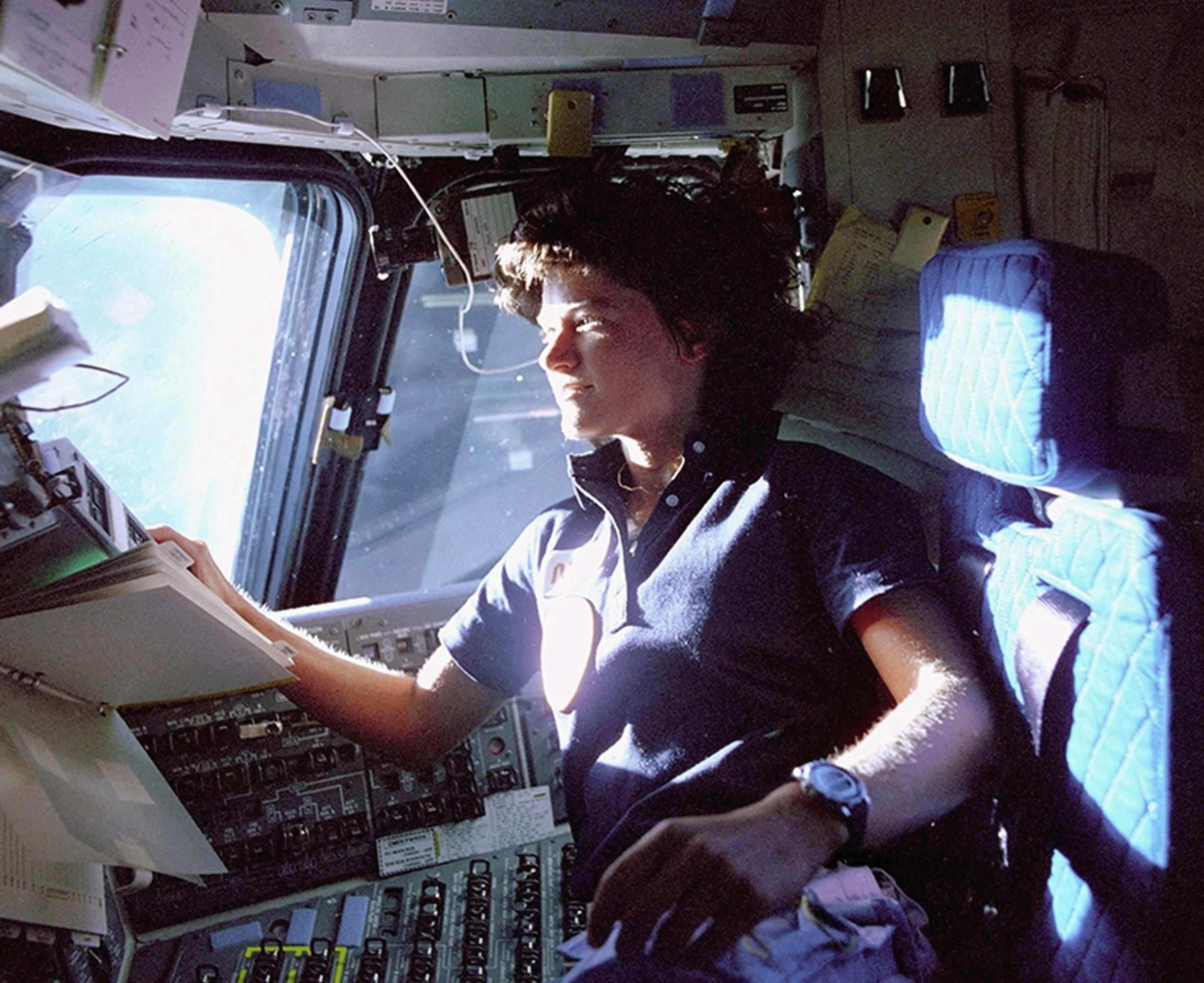 Sally Ride was a mission specialist on STS-7. In this image, she monitors control panels from the pilot's chair on the flight deck.