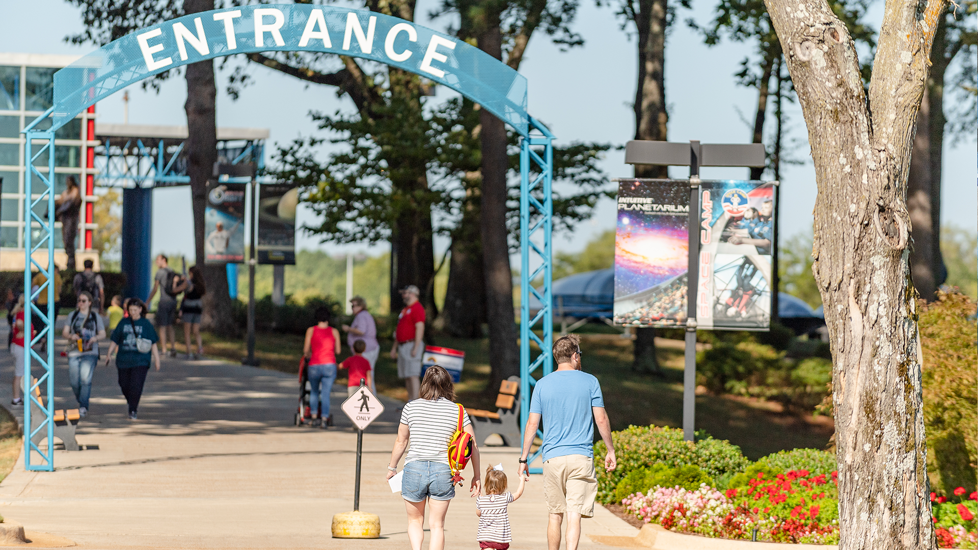 Parents hold the hand of their child as they approach the entrance of the U.S. Space & Rocket Center