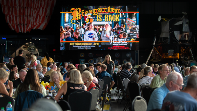 The Saturn V hall is full of individuals enjoying food and drink with family and friends.