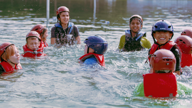 Trainees smile in floatation devices from the water of the Aviation Challenge lake