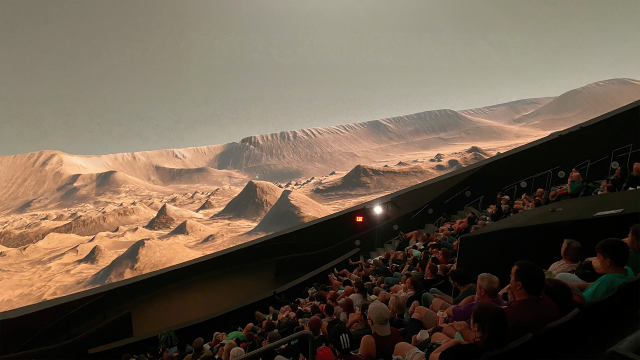 A captivated audience looks up at a Martian landscape shown on a large dome screen